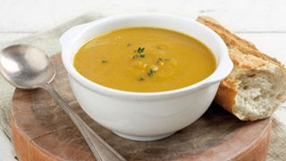 Carrot, Sweet Potato and Ginger soup served in a white bowl and crusty bread