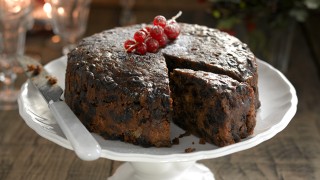 Christmas cake served on a white serving dish with a piece cut out