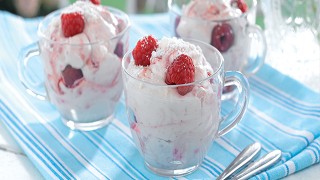 Raspberry Eton Mess served in glass cups on a blue tablecloth