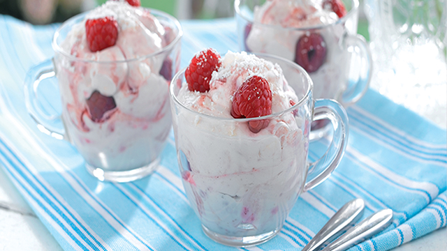 Raspberry Eton Mess served in glass cups on a blue tablecloth