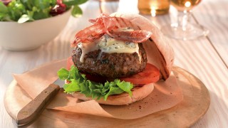 Homemade burger with bacon and cheese served on a burger bun with lettuce and tomato