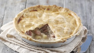 Huntingdon Fidget Pie served in a white dish with a slice removed to show the filling