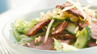 Lemon marinated duck breast salad served with the accompanying sauce and lemon wedges in a bowl