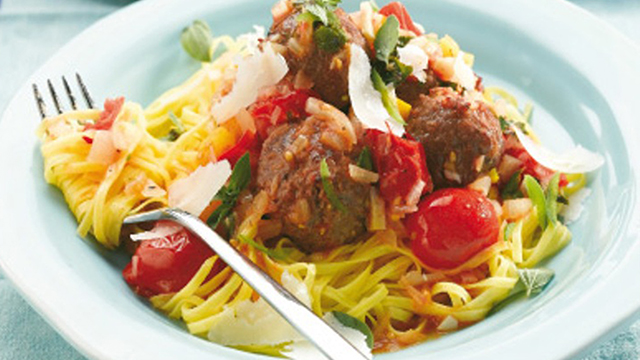 Mediterranean meatballs served with pasta and vegetables, topped with parmesan in a bowl
