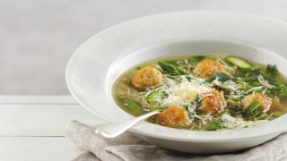 Spring Minestrone Soup with Chicken Meatballs served in a white dish with a sprinkling of parmesan