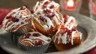 Mini Cranberry and White Chocolate Muffins decorated with icing and cranberries served in a grey dish