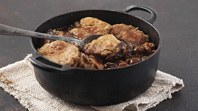 Minty Lamb Cobbler served in a casserole dish with a spoon lifting out the topping