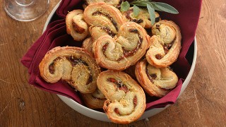 Mini pesto and roast pepper palmiers, served in a white dish with a sprinkling of parmesan