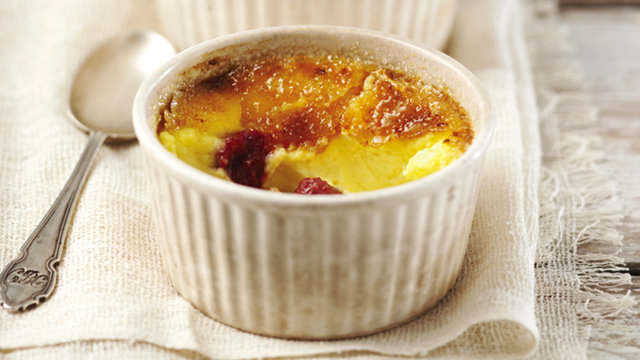 Raspberry Crème Brulee served in a white ramekinwith a portion missing to see the filling