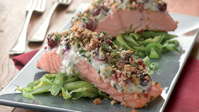 Salmon with a cranberry and walnut crust served on a bed of green vegetables