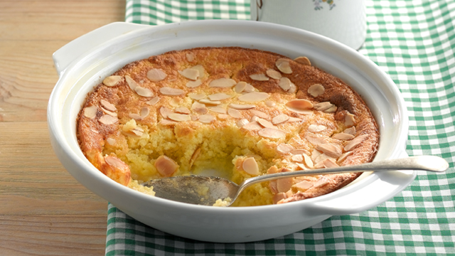 Self-saucing Lemon Sponge served ina white dish with a portion removed to see the filling