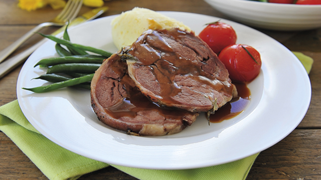 Slow cooked lamb shoulder served with vegetables and gravy on a white plate