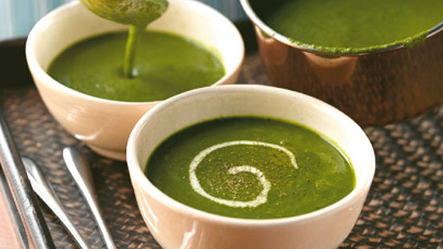 Spinach soup served in a bowl with a swirl of cream and black pepper
