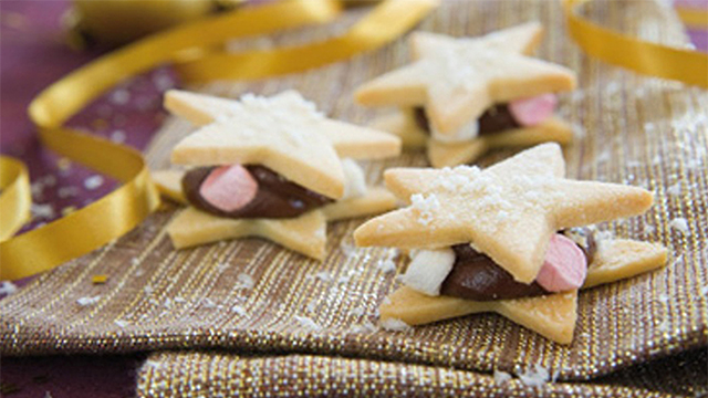 Star shortbread served on a gold and purple napkin surrounded by fake snow and gold stars