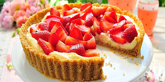 English Strawberry and Mascarpone Tart on a white dish with a slice missing to show the filling