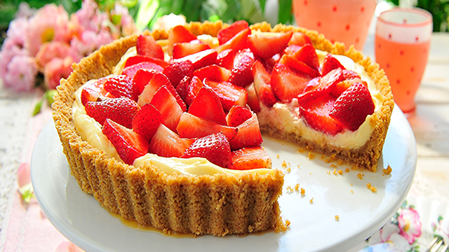 English Strawberry and Mascarpone Tart on a white dish with a slice missing to show the filling