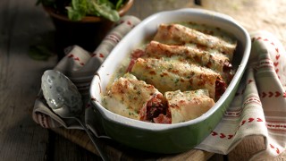 Vegetarian Cannelloni served in a green dish on top of a white and red towel