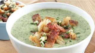 Watercress and Stilton soup topped with crispy bacon, served in a bowl with crusty bread