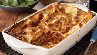 Beef lasagne cooked in a white dish with a portion missing