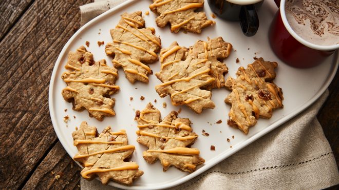 Oat and Toffee Leaf Biscuits served on a white tray next to a hot chocolate