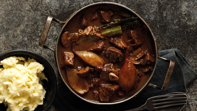 Slow-Cooked Boeuf Bourguignon served in a pan with a dish of mash potato to the side