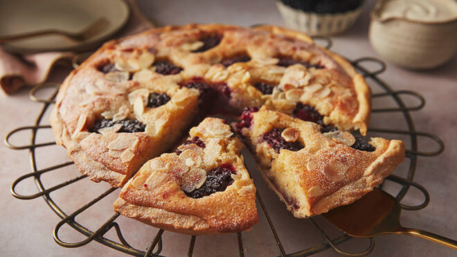 Blackberry frangipane tart with two slices cut out, sat on a wire rack