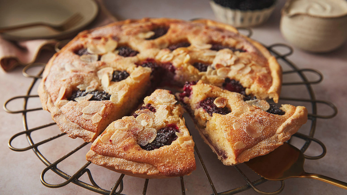 Blackberry frangipane tart with two slices cut out, sat on a wire rack
