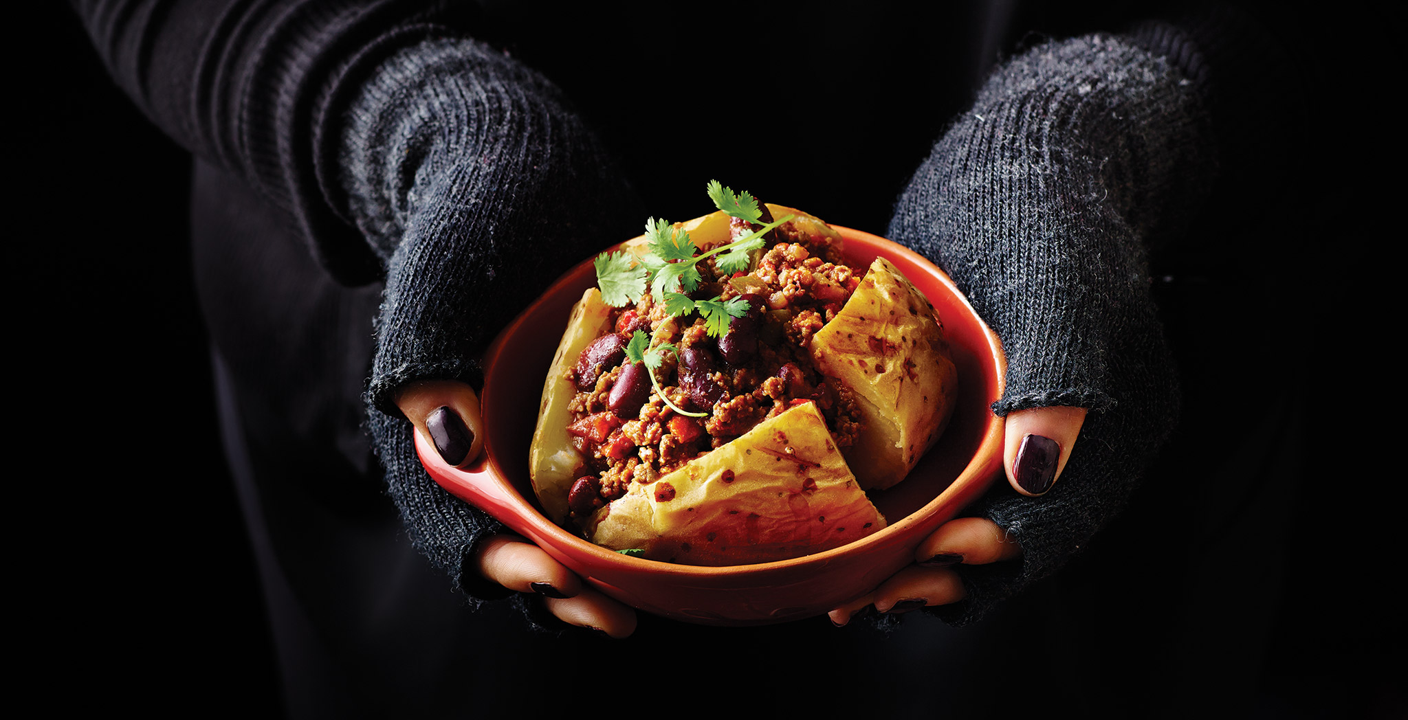 Jacket Potato with Chilli Con Carne in a bowl topped with coriander