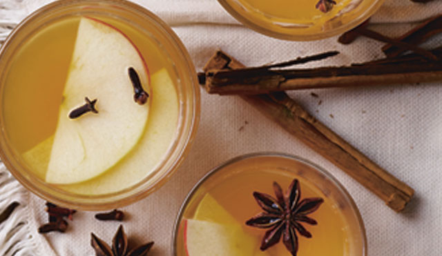 Warming Party Punch served in three glasses with apple slices, star anise and cinnamon sticks