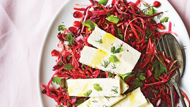 Beetroot and Pomegranate Slaw topped with slices of feta and dill on a white plate