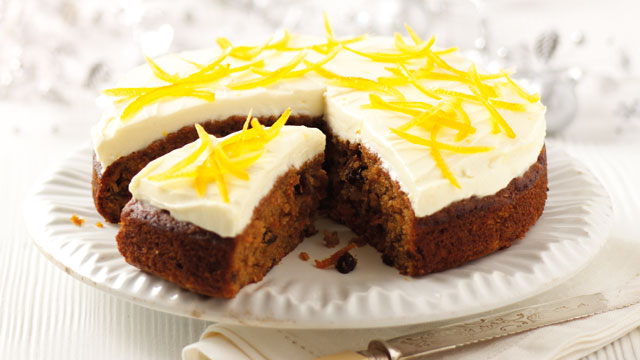 Old Fashioned Carrot Cake with Lemon and Cream Cheese Frosting served on a white plate with a slice cut to show the inside