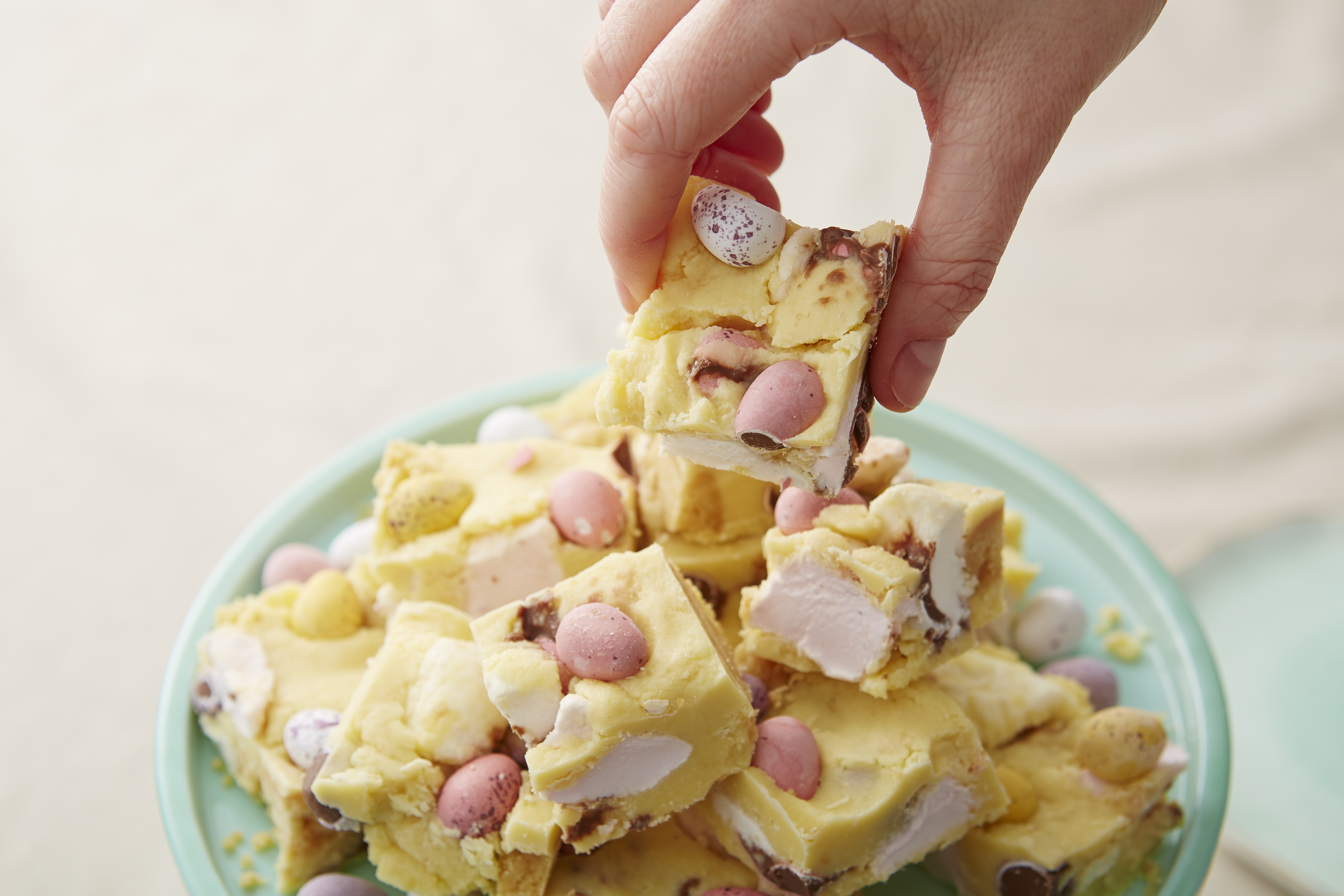 No Bake White Chocolate Mini Egg Rocky Road cut into squares and served on a turquoise plate