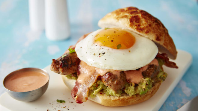 Bank Holiday Brunch Stack served on a white plate. With the top bread removed to show the egg