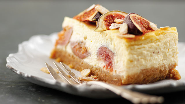 A slice of Baked Fig and Amaretto Cheesecake served on a white plate with a dessert fork