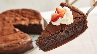 Flourless Chocolate Cake, with a slice removed, topped with whipped cream and strawberries