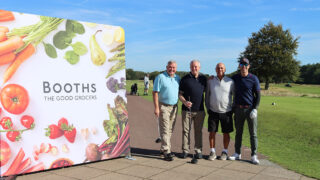 Image of four golfers stood next to a Booths banner