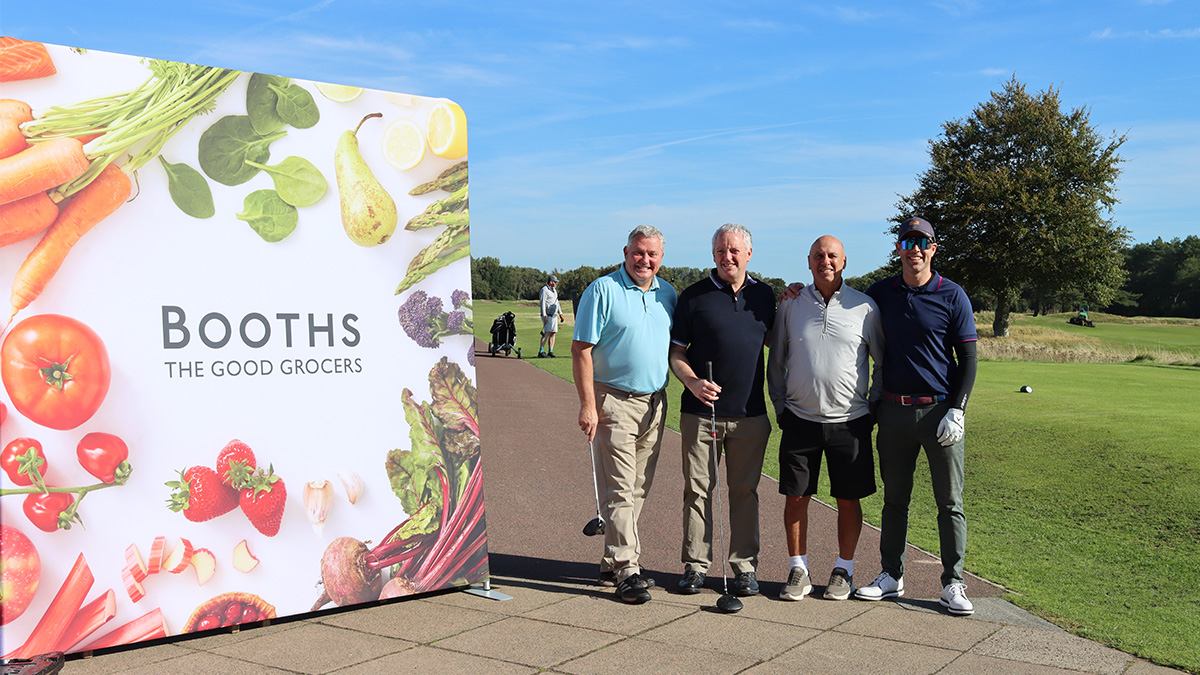 Image of four golfers stood next to a Booths banner