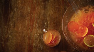 Halloween Party punch served in a glass bowl with a clear plastic spoon, next to a cup of the punch