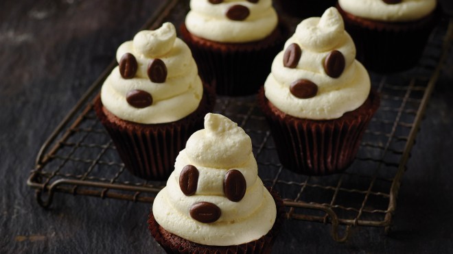 Three ghostly cupcakes sitting on a wire rack