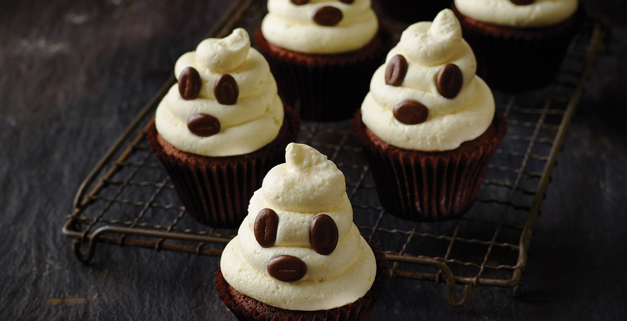 Three ghostly cupcakes sitting on a wire rack