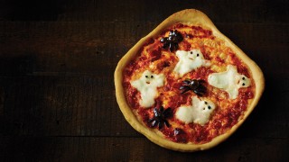 One ghoulish pizza topped with mozzarella ghosts and olive spiders