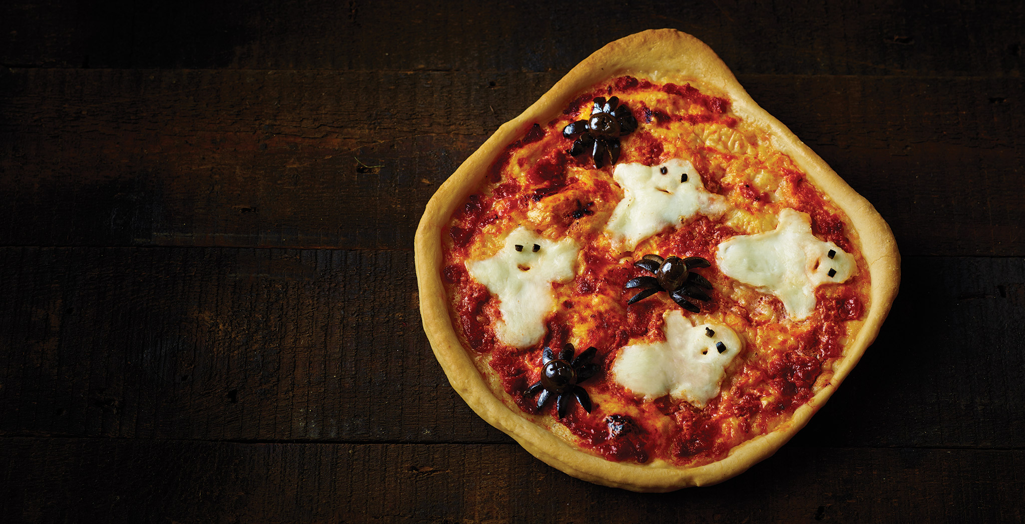 One ghoulish pizza topped with mozzarella ghosts and olive spiders