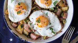 One-Pan Leftover Ham and Potato Hash served in a white and blue dish sprinkled with chilli flakes and coriander