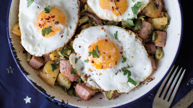 One-Pan Leftover Ham and Potato Hash served in a white and blue dish sprinkled with chilli flakes and coriander