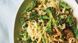 Shiitake Mushroom and Leek Thai Noodles served with broccoli in a white bowl on a white table cloth