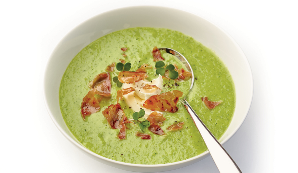 Chilled Yorkshire Pea, Watercress and Cumbrian Ham soup served in a white bowl and topped with a swirl of creme fraiche