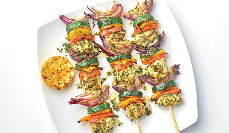 Fish Kebabs with Chermoula Sauce served on a white plate with a wedge of grilled lemon