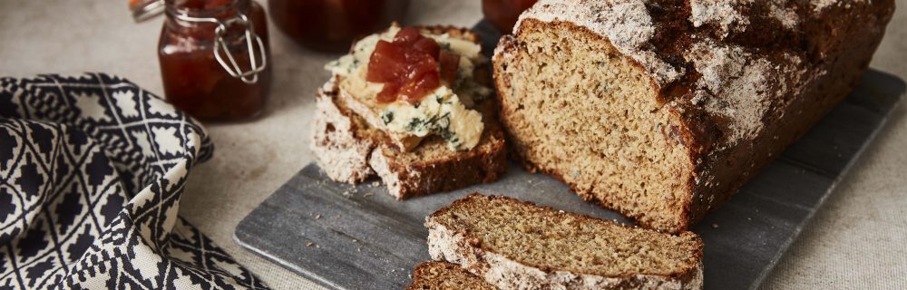 Pear, Blue cheese and Prosciutto Soda Bread sliced and served on a slate, with a jar of chutney