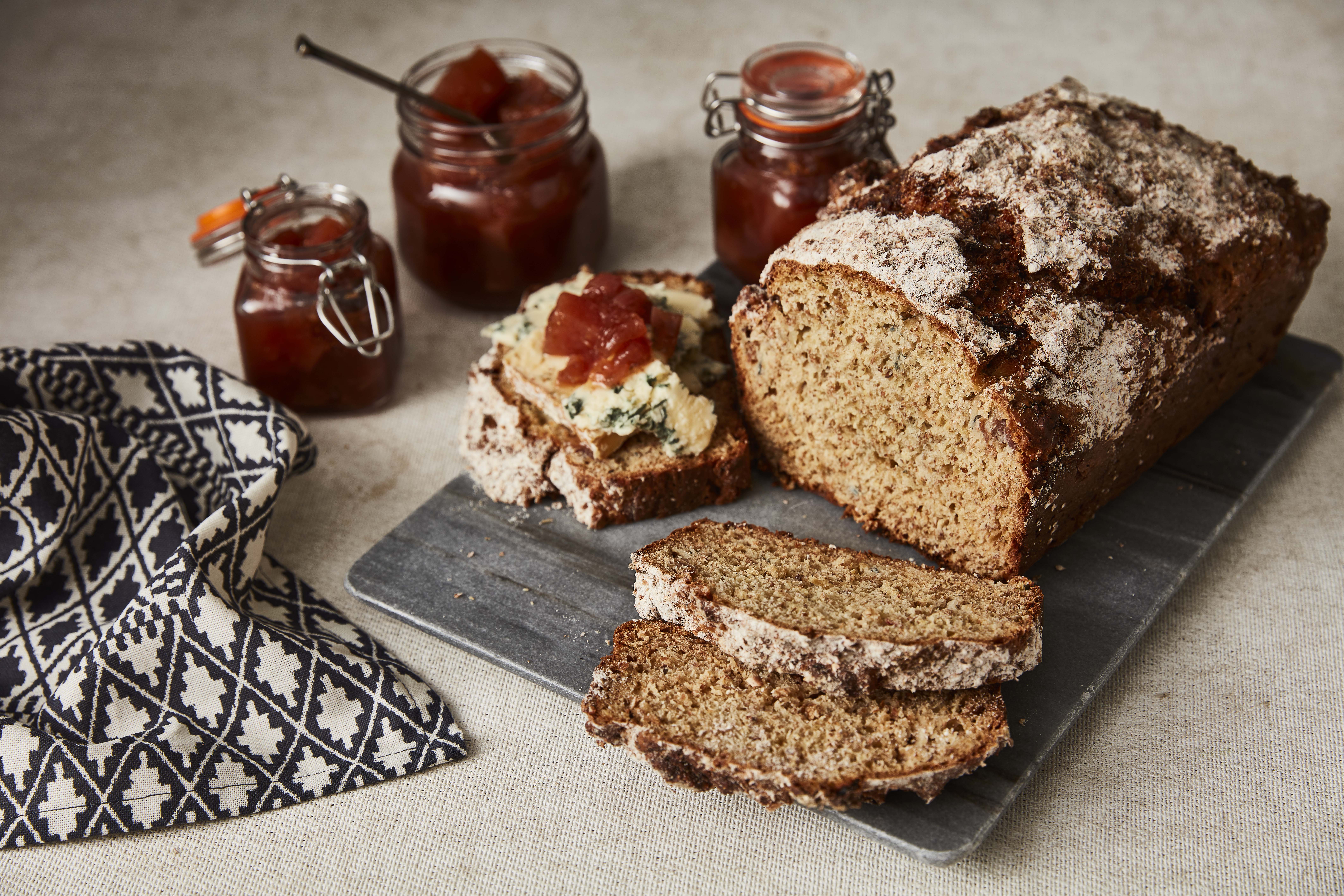 Pear, Blue cheese and Prosciutto Soda Bread sliced and served on a slate, with a jar of chutney