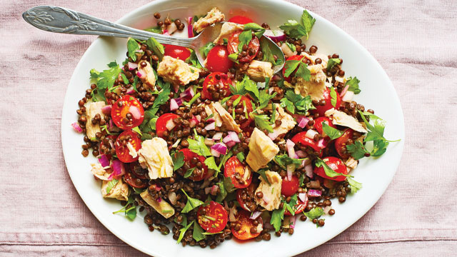 Puy Lentil and Tuna Salad served in a white dish with a spoon on top of a pink table cloth